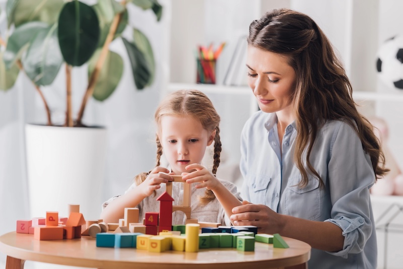 Mother and daughter with autism playing with wooden educational toys