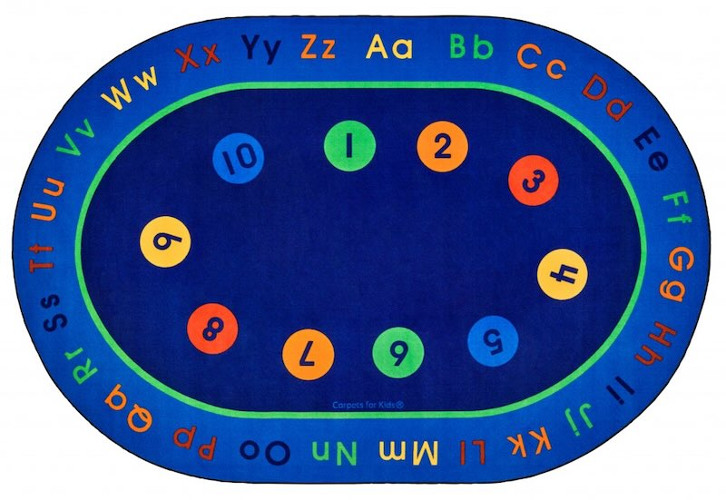 A dark blue background colored classroom carpet where the letters of alphabet in lower and uppercase pairs are printed in different colors all around and the numbers from 0-9 are printed in the middle